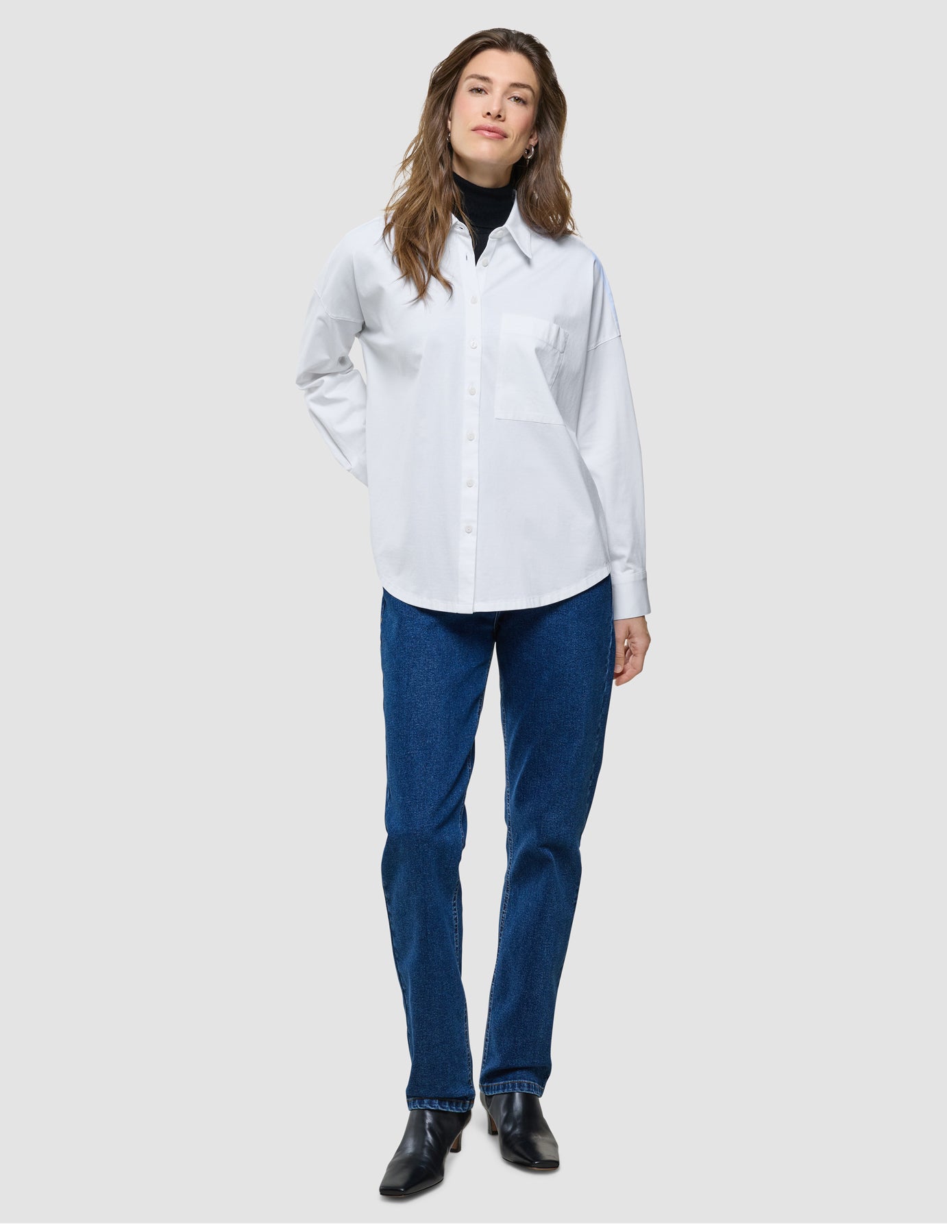 Oversized Long Sleeve Shirt i Off White, helfigur med model iført hvid skjorte og blå jeans.